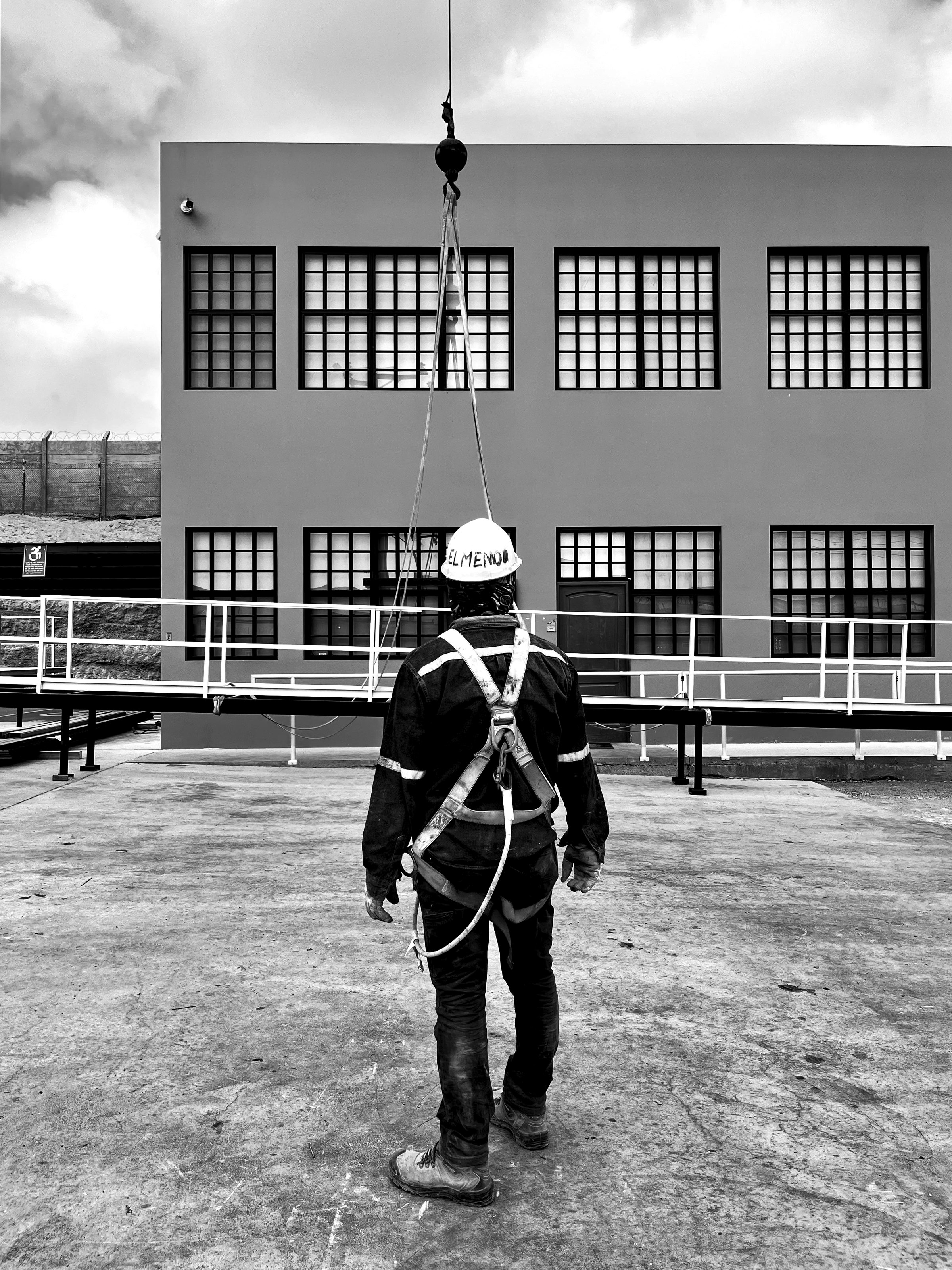Trabajador con arnés frente a edificio, enganchado a una grúa