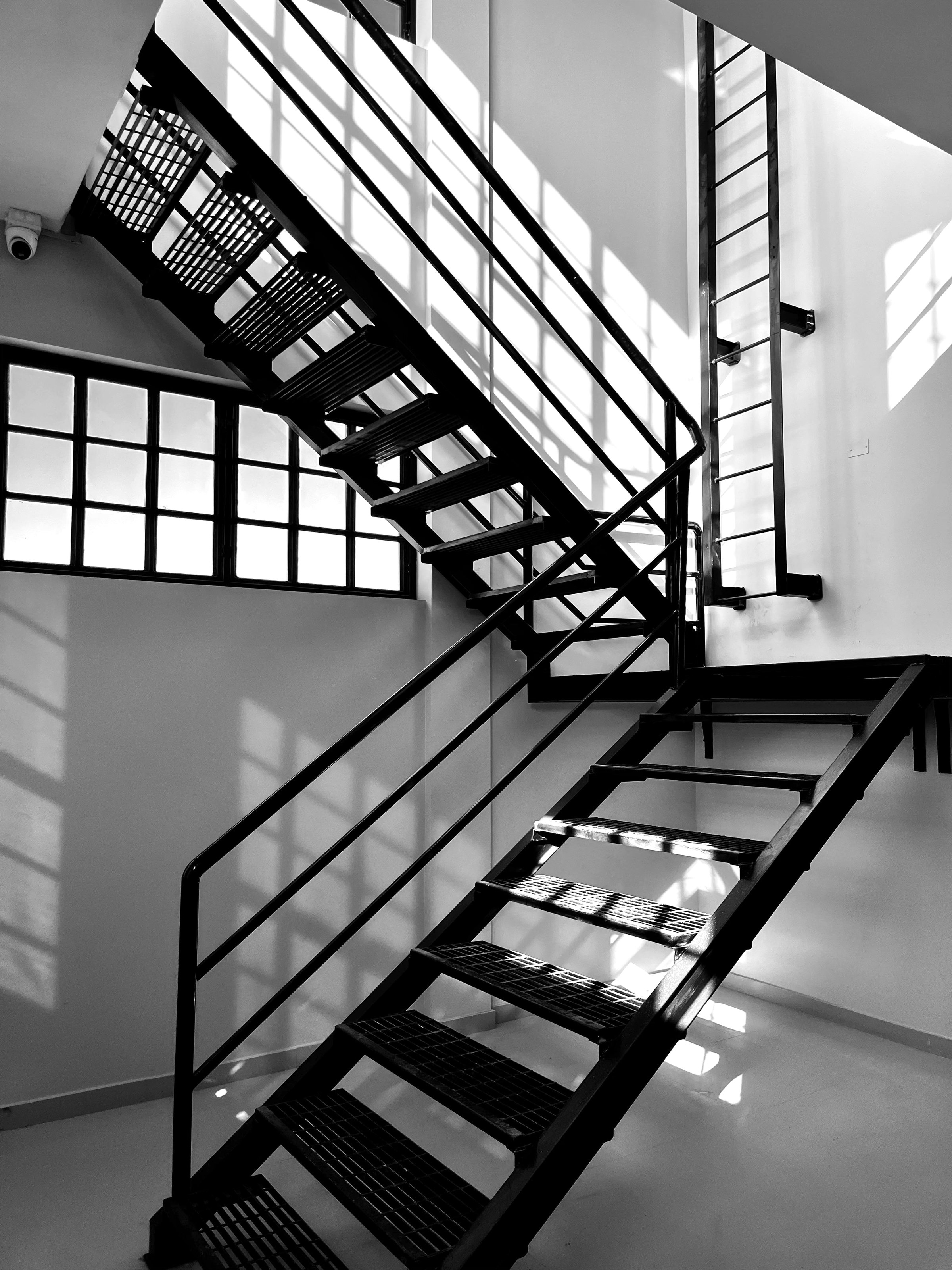 Escalera metálica industrial con luz natural entrando por ventanas