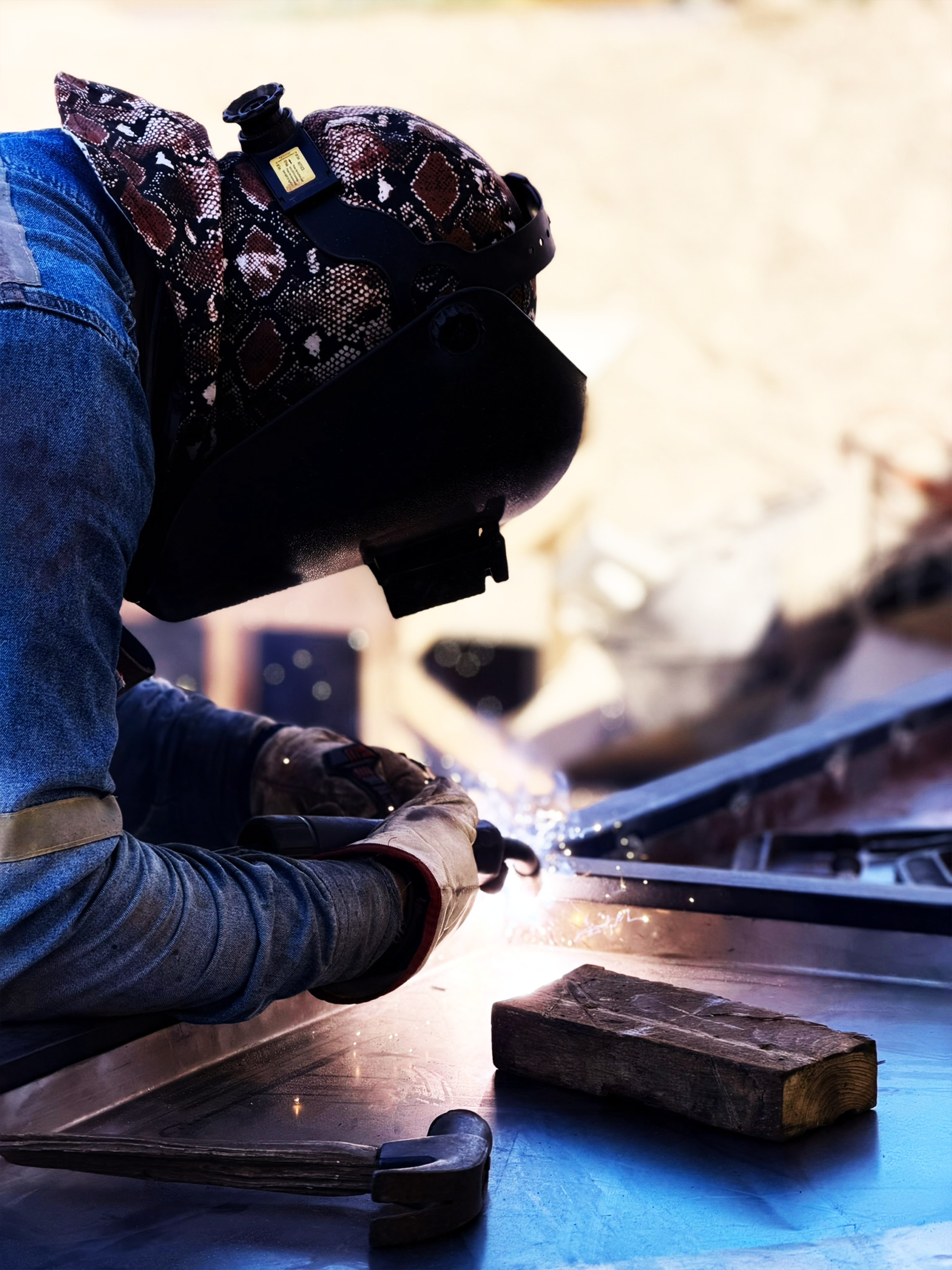Trabajador soldando estructura metálica con máscara de soldar, chispas en primer plano